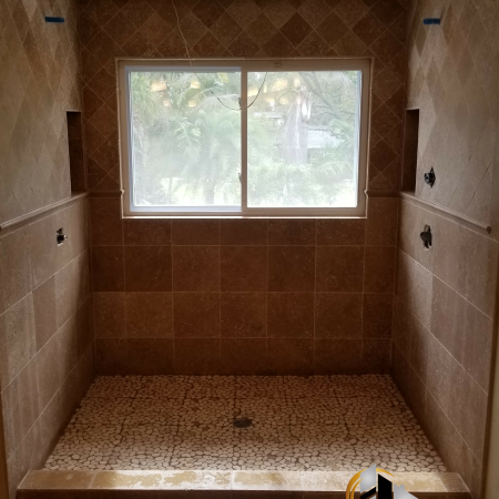 Ceramic tile installated two ways on the walls with pebble tile mosaic floor and shower boxes